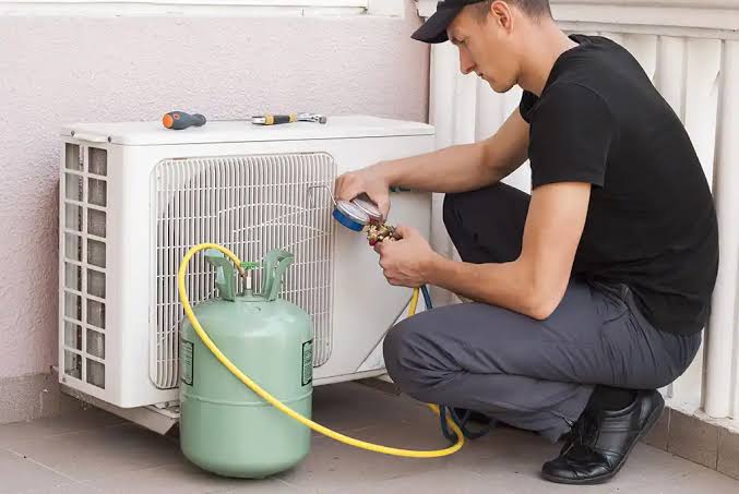 Technician checking a compact outdoor air conditioner with service gauges