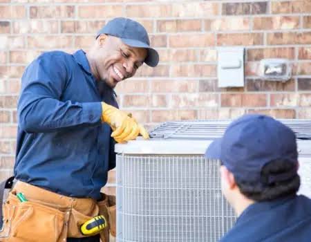 Two technicians inspecting an outdoor air conditioner beside a brick home