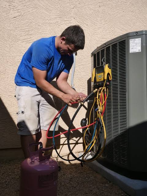 Technician connecting service gauges to a residential air conditioning unit