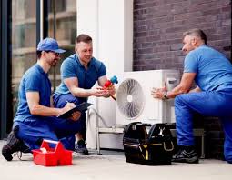 Three technicians checking a compact outdoor air conditioning unit